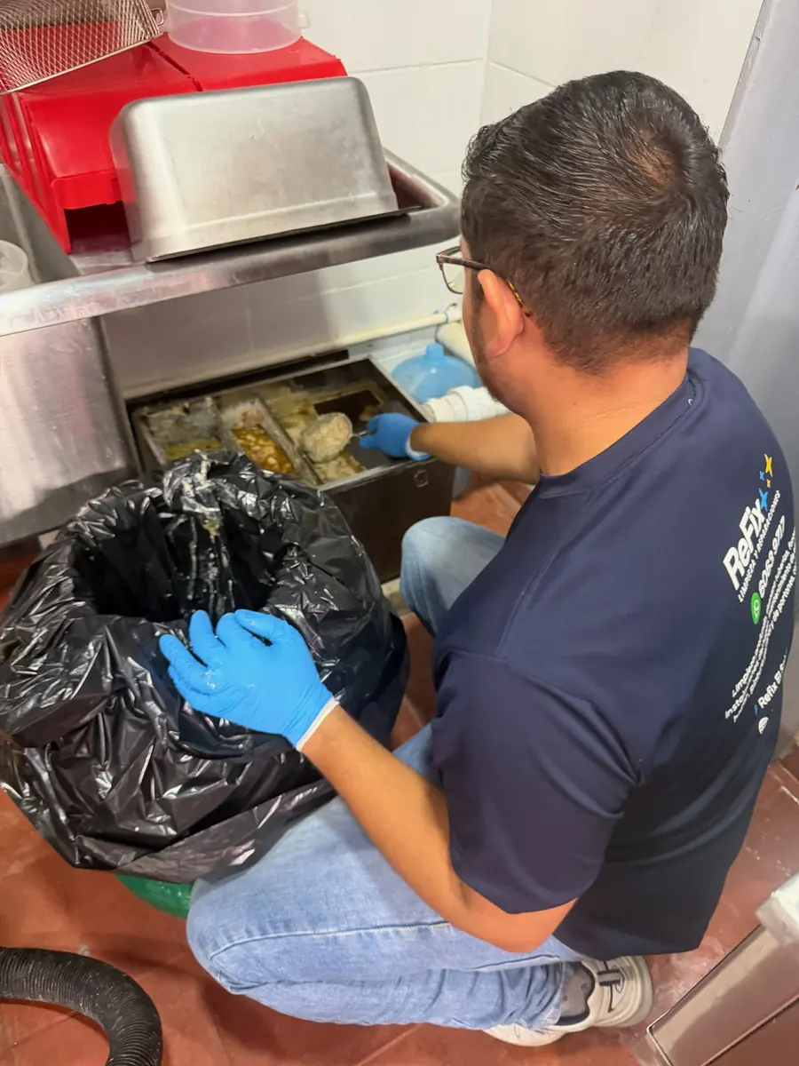 Técnico de ReFix limpiando una trampa de grasa en la cocina de un restaurante